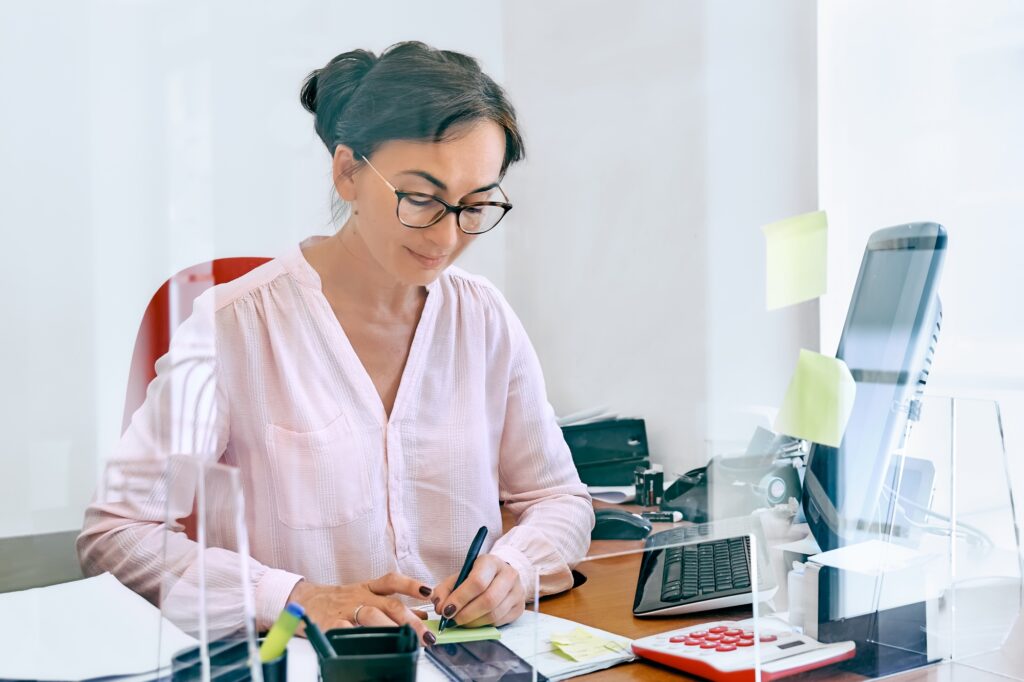 Female professional working at her desk with documents and a calculator, representing expert talent placed through finance and accounting staffing solutions.