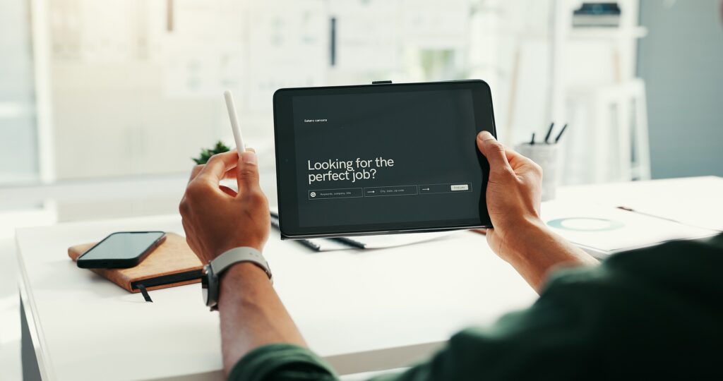 Professional reviewing a digital job platform on a tablet in a modern office, symbolizing recruiter help finding a job through tailored search and support tools. 