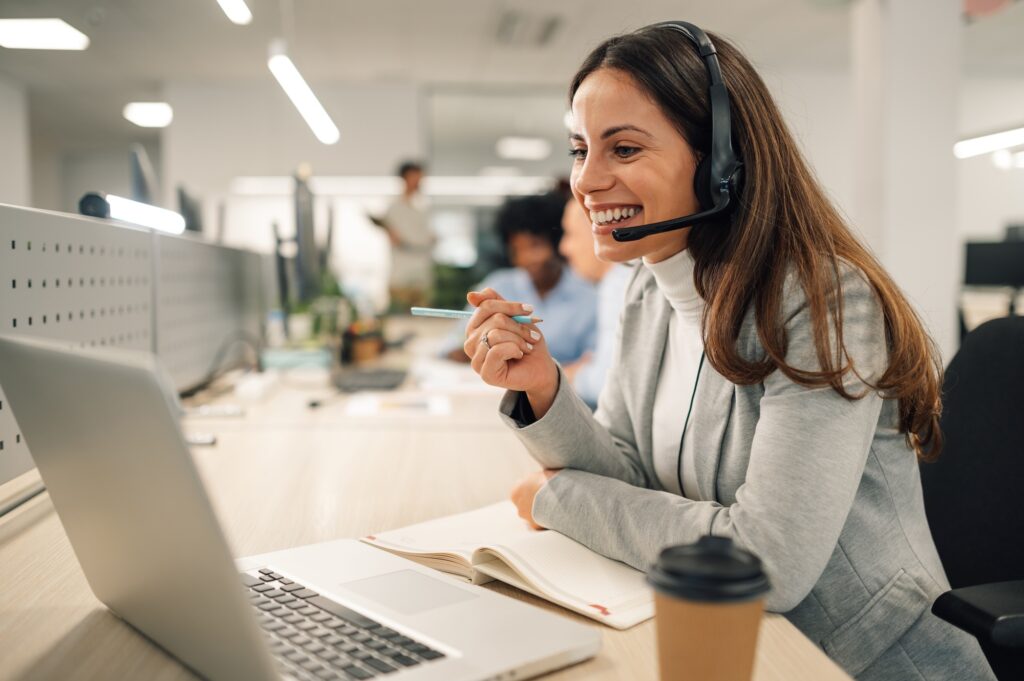 Smiling professional receptionist on a headset during a video call—illustrating the reliability and adaptability of temp receptionists for hire in modern offices.