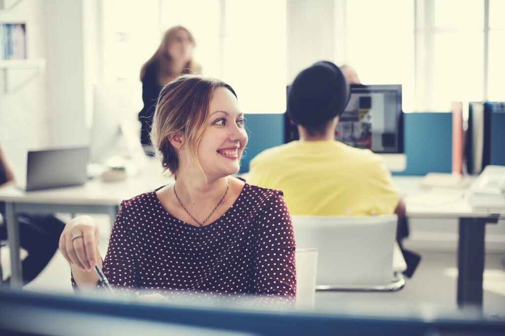 Smiling employee in a vibrant office environment—reflecting the workplace readiness and culture fit delivered by a top-tier clerical staffing agency.