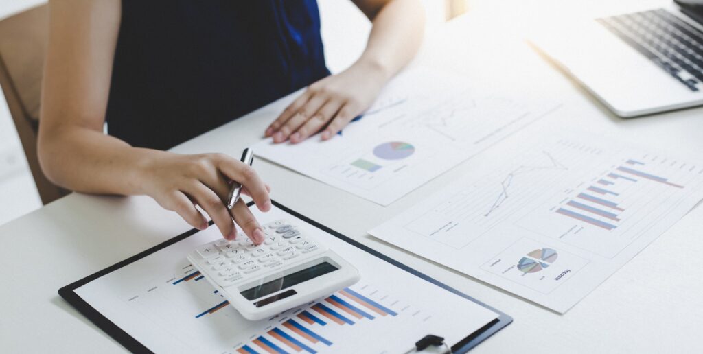 Professional analyzing financial charts with a calculator at a desk, representing precision-driven finance and accounting staffing solutions.