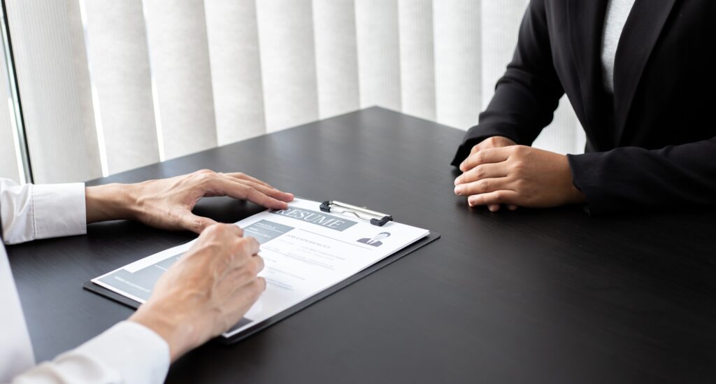 Professional interview scene showcasing global staffing solutions during a corporate hiring process, with a recruiter reviewing a candidate's resume at a modern office desk.