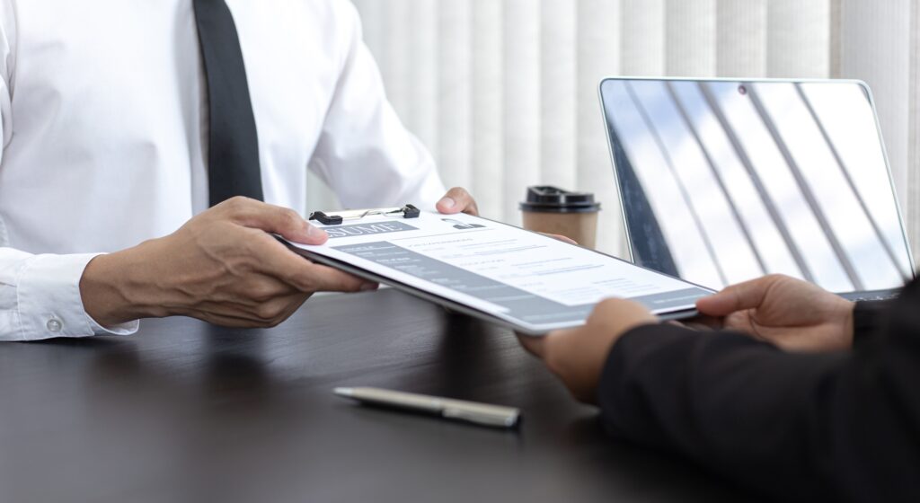 Professional handing over a resume during a formal interview, reflecting the trust and professionalism driven by strong staffing agency leadership.