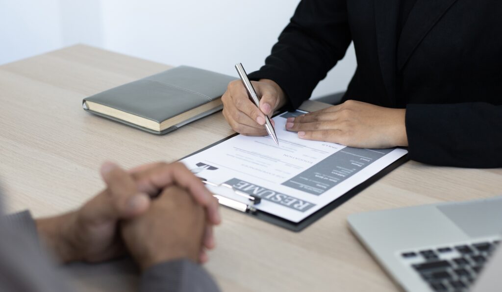 LH Global Consulting recruiter reviewing a candidate's resume during a corporate job interview in a modern office setting.