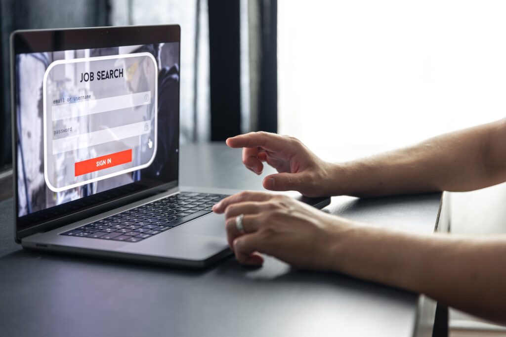 A person using a laptop with a job search portal on the screen, entering credentials to get matched with a job online.