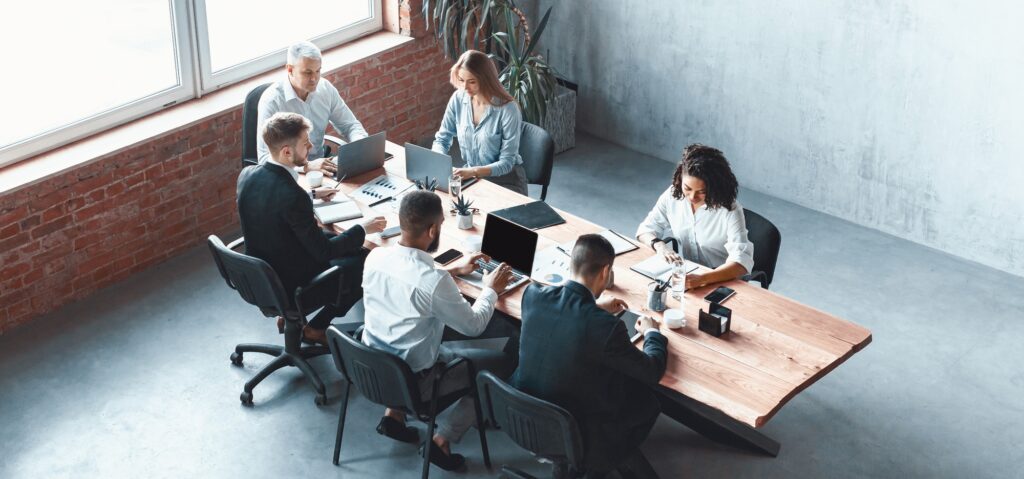 Corporate team strategizing around a conference table in a modern office, illustrating collaborative planning efforts involved in successful cybersecurity talent recruitment for enterprise-level protection.