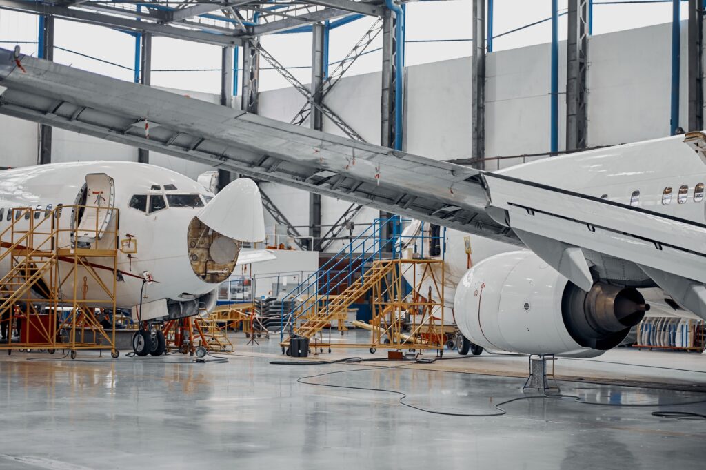 Aircraft maintenance facility with technicians working on commercial planes, illustrating staffing specialties in aviation and aerospace industries.