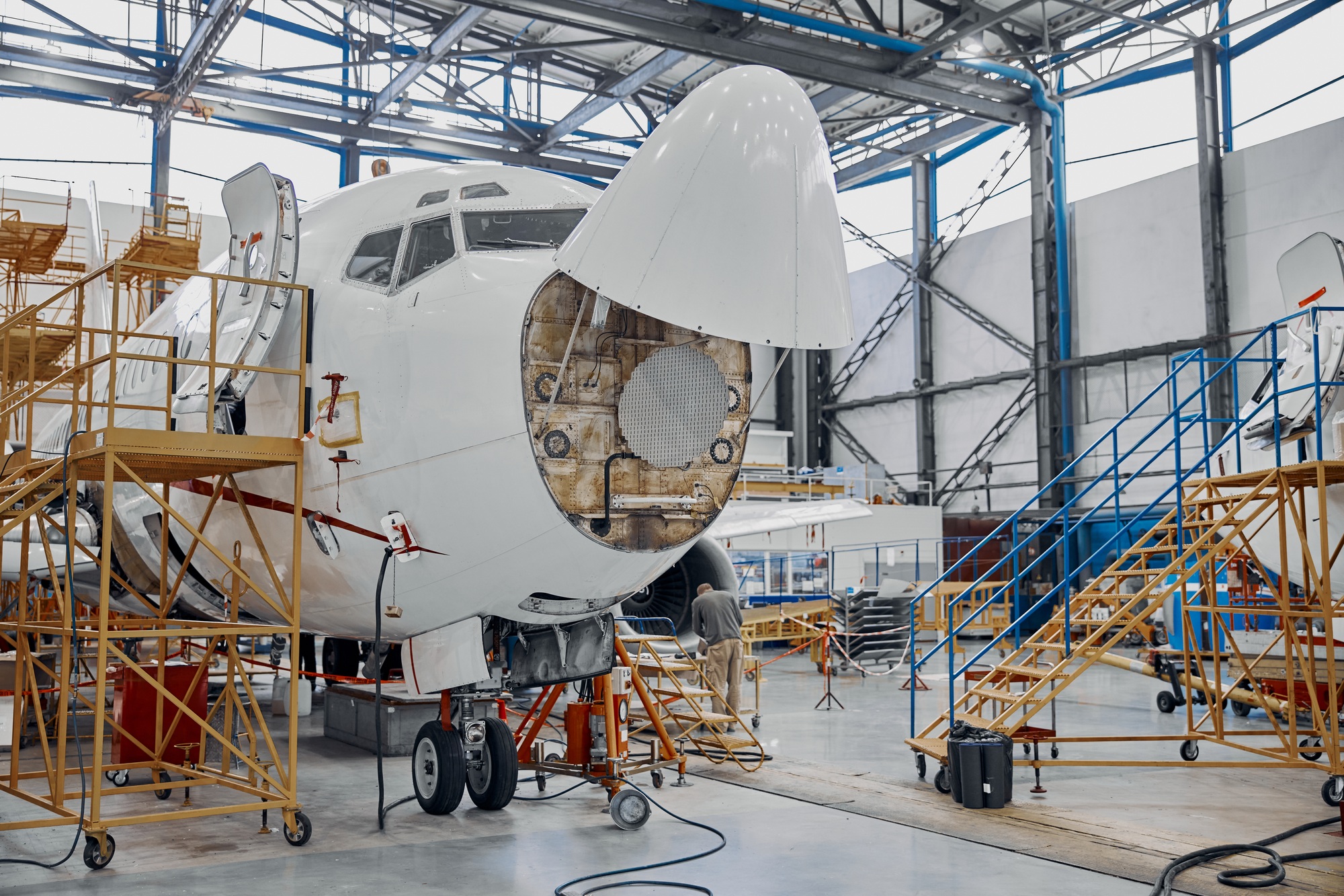 Aircraft nose section under maintenance in a modern hangar, showcasing aerospace innovation powered by additive manufacturing for precision components.