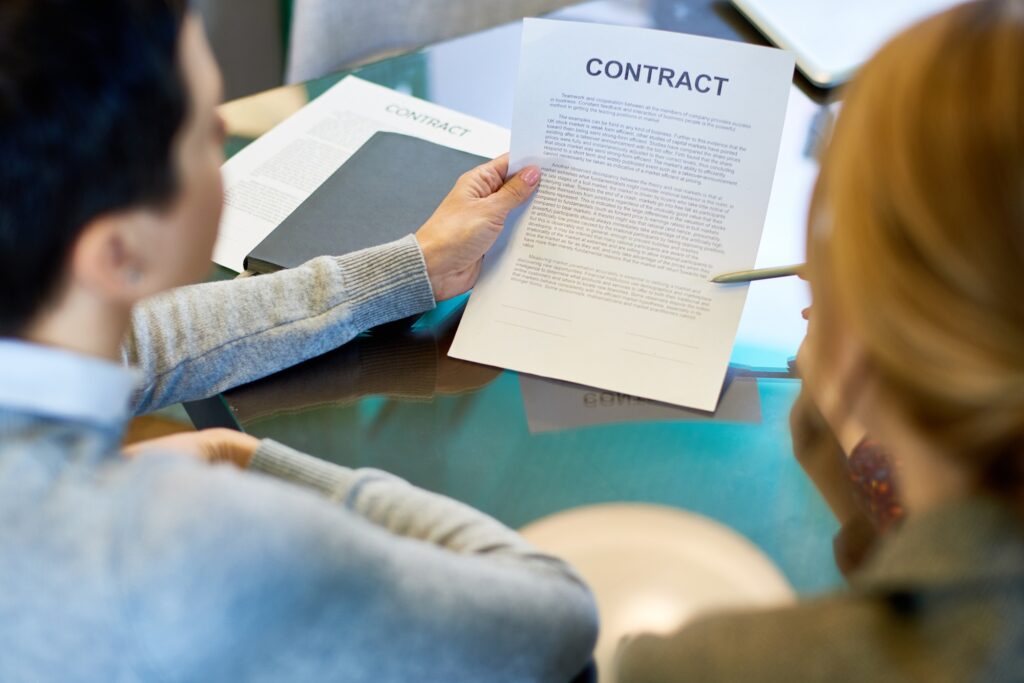 Business professionals reviewing a formal agreement at a meeting table, symbolizing the process companies follow to contract IT professionals for specialized technical projects.
