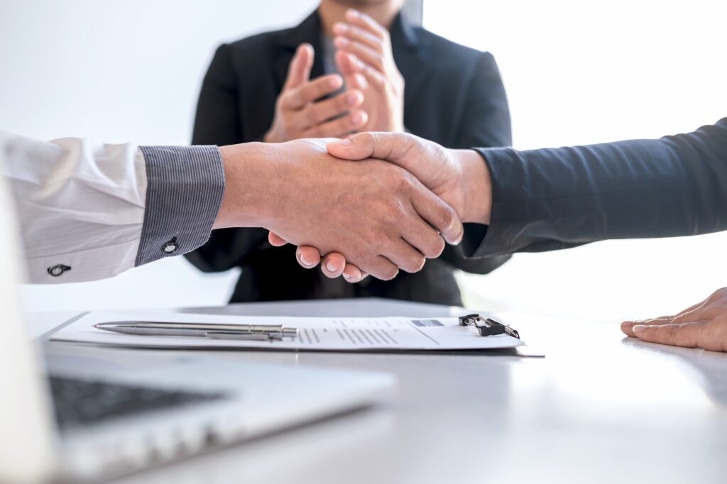 Successful job placement sealed with a handshake, symbolizing a professional partnership led by an international recruitment company during the hiring process.