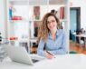 Portrait of a young woman working at desk, taking notes.